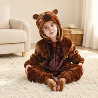 Child sitting on a rug in a brown teddy bear costume onesie