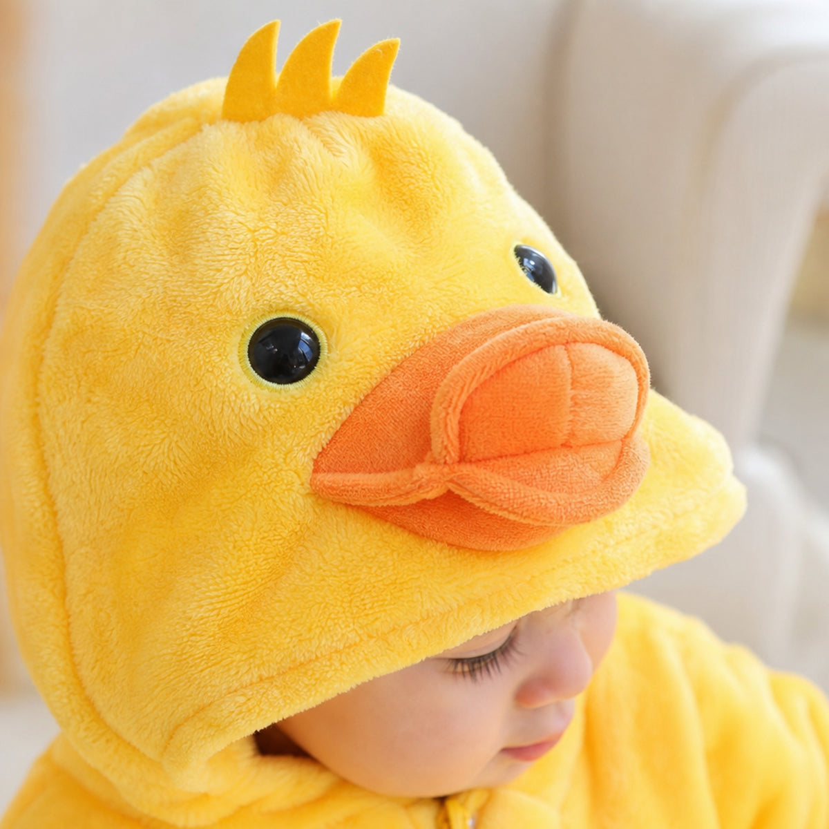 Close-up of the duckling hood with puffy orange beak, eyes and yellow felt crest